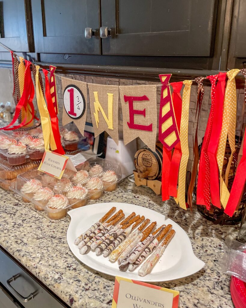 harry potter themed banner over birthday party cupcakes and dipped pretzel rods